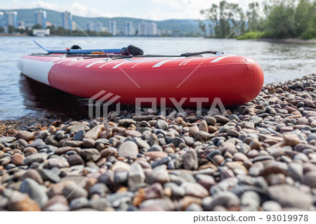 SUP board on the river bank. Paddle board on the lake shore. SUP board on the river bank. Paddle board on the lake shore. 93019978