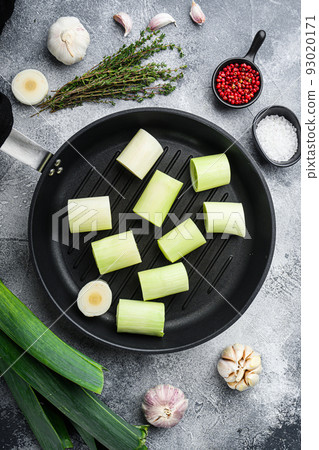 Raw braised Leeks on grill pan uncooked with herbs ingredients , on textured grey background top view. Raw braised Leeks on grill pan uncooked with herbs ingredients , on textured grey background top view. 93020171