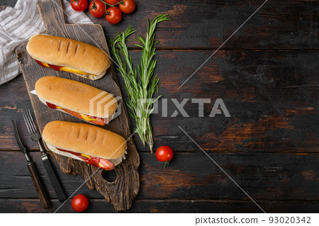 Hot dog grilled sausage in a bun with sauces, on old dark  wooden table background, top view flat lay, with copy space for text 93020342