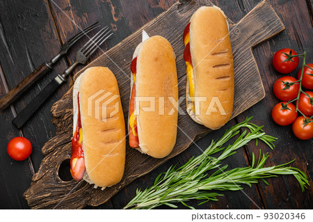 Hot dog with ketchup and yellow mustard, on old dark  wooden table background, top view flat lay 93020346