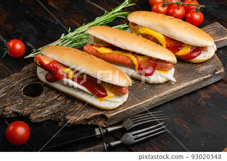 Hot dog grilled sausage in a bun with sauces, on old dark wooden table background Hot dog grilled sausage in a bun with sauces, on old dark wooden table background 93020348