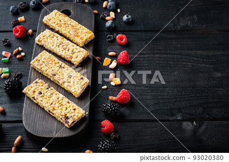 Raw organic granola bars with seeds and nuts with copy space, on black wooden table Raw organic granola bars with seeds and nuts with copy space, on black wooden table 93020380