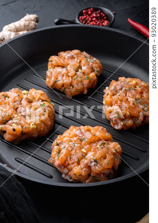 Raw quick asian salmon cutlets, on black textured background Raw quick asian salmon cutlets, on black textured background 93020389