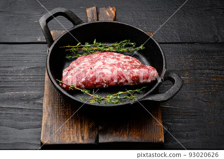 Organic raw ground beef, round patties, in cast iron frying pan, on black wooden table background, with copy space for text Organic raw ground beef, round patties, in cast iron frying pan, on black wooden table background, with copy space for text 93020626
