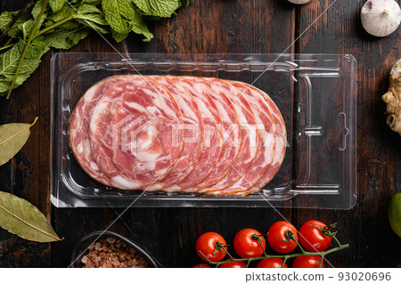 Dry sliced sausages packed in vacuum plastic, on old dark wooden table background, top view flat lay Dry sliced sausages packed in vacuum plastic, on old dark wooden table background, top view flat lay 93020696