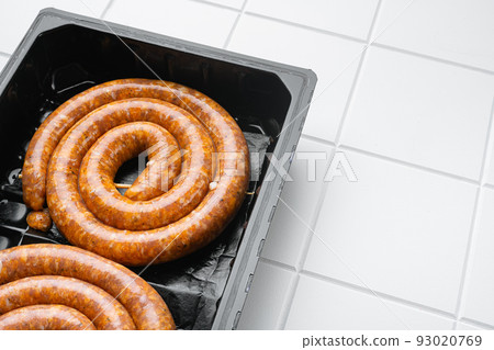 Cumberland sausage, spiral pork sausage, on white ceramic squared tile table background, with copy space for text 93020769