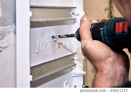 Power drill at electrical work is used to drilling hole in distribution board. 93021137