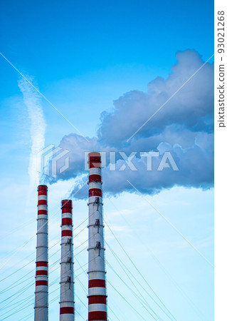 Air pollution. Thick smoke from chimneys in industrial plant. Manufacturing factory pollutes environment. Smoking chimneys against blue sky. Vertical photo. Air pollution. Thick smoke from chimneys in industrial plant. Manufacturing factory pollutes environment. Smoking chimneys against blue sky. Vertical photo. 93021268