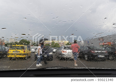 Raindrops on the window glass with outline of a car and a person Raindrops on the window glass with outline of a car and a person 93021340