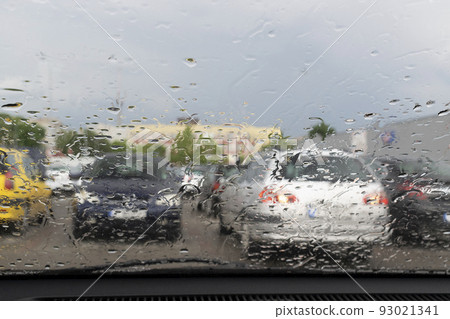 Raindrops on the window glass with outline of a car and a person Raindrops on the window glass with outline of a car and a person 93021341