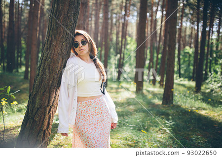 Young beautiful hippie woman walks in the summer forest laughs dances and enjoys life and nature Young beautiful hippie woman walks in the summer forest laughs dances and enjoys life and nature 93022650