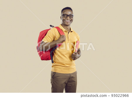 Happy African American student with books and backpack standing on beige studio background 93022966