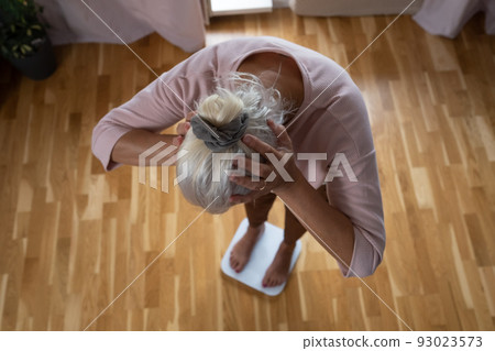 Woman stepping on floor scales, closeup. Weight control 93023573