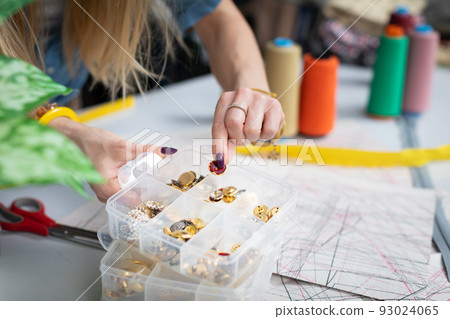 The clothing designer selects decorative accessories for the jacket. 93024065