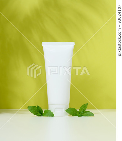 Empty white plastic tubes for cosmetics on a green background. Packaging for cream, gel 93024107