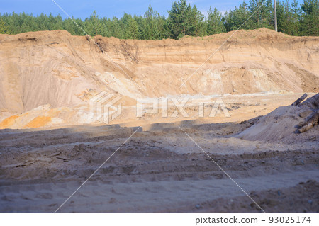 A deep sand pit with yellow and white sand with green trees along the edge 93025174