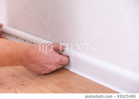 A man installs a floor skirting board. Fixing the 93025490