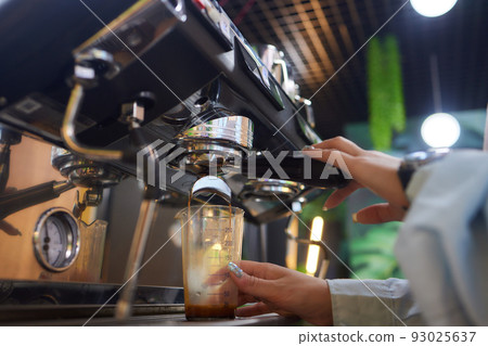 Top view shot of professional barista pouring milk from jar in to a cup of coffee, coffee being prepared by a barista. Focus on hands holding cup of coffee. Top view shot of professional barista pouring milk from jar in to a cup of coffee, coffee being prepared by a barista. Focus on hands holding cup of coffee. 93025637