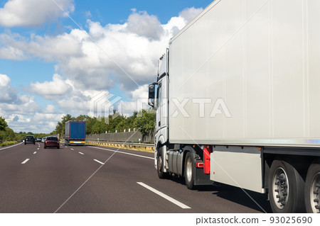 White blank modern delivery big shipment cargo commercial semi trailer truck moving fast on motorway road city urban suburb. Business distribution logistics service. Lorry driving highway sunny day White blank modern delivery big shipment cargo commercial semi trailer truck moving fast on motorway road city urban suburb. Business distribution logistics service. Lorry driving highway sunny day 93025690