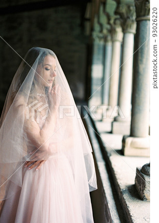 Bride in a veil stands on the terrace near the columns Bride in a veil stands on the terrace near the columns 93026220