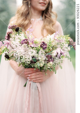 Wedding bouquet of wild flowers in the hands of the bride. Close-up Wedding bouquet of wild flowers in the hands of the bride. Close-up 93026221