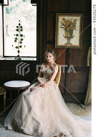 Bride sits on a chair at a table near the window of an old villa. Como, Italy 93026278