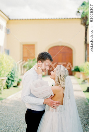 Bride and groom hugging in front of a building in the garden Bride and groom hugging in front of a building in the garden 93026307