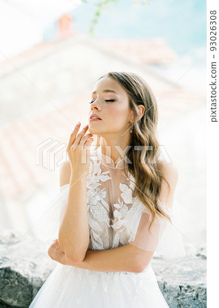 Bride in a white dress touches her chin with her fingers. Portrait Bride in a white dress touches her chin with her fingers. Portrait 93026308
