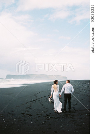Bride and groom walking along Vik beach in Iceland 93026335