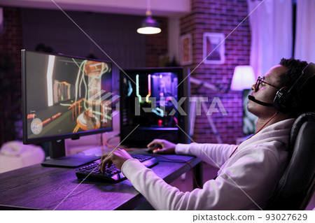 Internet vlogger broadcasting live video games play on computer, having fun with online game championship tournament on stream. Virtual gamer playing esport competition at desk with neon lights. Internet vlogger broadcasting live video games play on computer, having fun with online game championship tournament on stream. Virtual gamer playing esport competition at desk with neon lights. 93027629