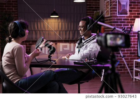 Man and woman recording podcast conversation on camera, vlogging discussion for social media content. Lifestyle blogger and female guest filming live broadcast stream on channel. Man and woman recording podcast conversation on camera, vlogging discussion for social media content. Lifestyle blogger and female guest filming live broadcast stream on channel. 93027643