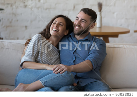 Happy young adult couple in love, enjoying leisure on couch Happy young adult couple in love, enjoying leisure on couch 93028025