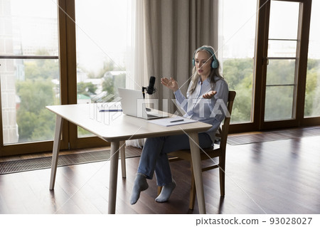 Pretty mature professional blogger recording podcast at home Pretty mature professional blogger recording podcast at home 93028027