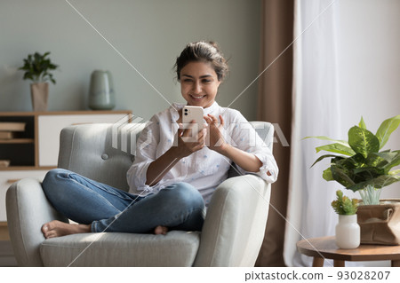 Happy pretty Indian girl relaxing at home, resting in armchair 93028207