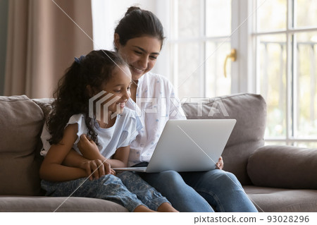 Happy young Indian mother and curious kid watching movie Happy young Indian mother and curious kid watching movie 93028296