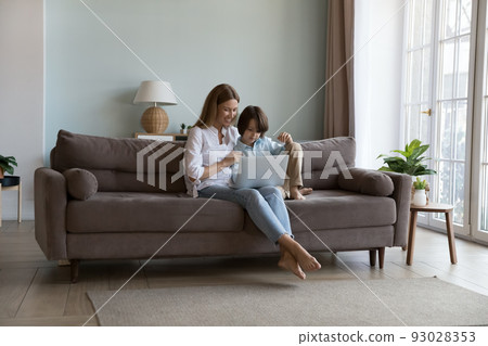 Woman and son sit on sofa spend leisure using laptop 93028353