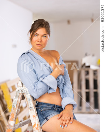 Half-naked girl in short shorts posing in cottage under construction Half-naked girl in short shorts posing in cottage under construction 93031575