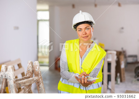 Positive woman builder checking project documentation Positive woman builder checking project documentation 93031662