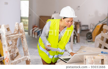 Focused female civil engineer using laptop at construction site Focused female civil engineer using laptop at construction site 93031666