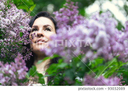 Portrait of an attractive woman surrounded by lilac bushes. Spring and summer, seasonal photos. Front view. Portrait of an attractive woman surrounded by lilac bushes. Spring and summer, seasonal photos. Front view. 93032089