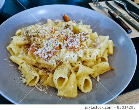 Penne pasta carbonara on white sauce with bacon and extra topping cheese served on blue plate Penne pasta carbonara on white sauce with bacon and extra topping cheese served on blue plate 93034295