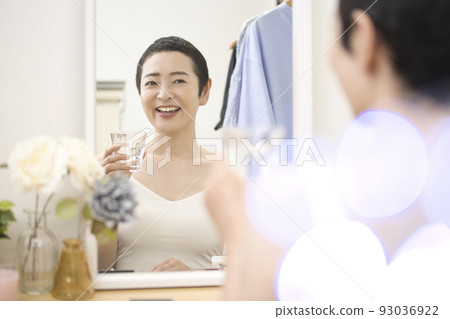 Beauty Middle-aged woman with short hair taking medicine in front of the mirror Beauty Middle-aged woman with short hair taking medicine in front of the mirror 93036922