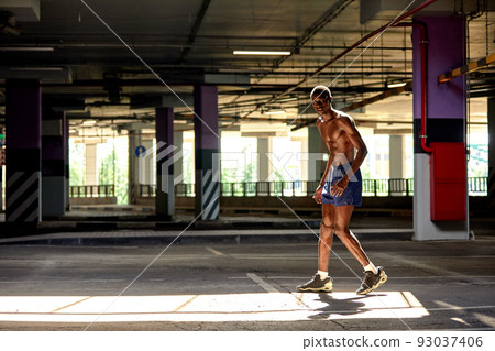 Handsome afro American sportman standing on the street while taking break after training. Black male having rest after workout 93037406