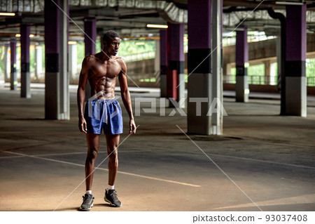 Handsome afro American sportman standing on the street while taking break after training. Black male having rest after workout Handsome afro American sportman standing on the street while taking break after training. Black male having rest after workout 93037408
