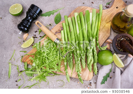 Green organic natural Asparagus on wooden cutting board at kitchen table Green organic natural Asparagus on wooden cutting board at kitchen table 93038546