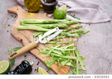 Green organic natural Asparagus on wooden cutting board at kitchen table Green organic natural Asparagus on wooden cutting board at kitchen table 93038563