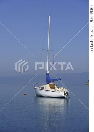 Albania, May 12, 2022 - Sail boat and reflection anchored near shore 93039302