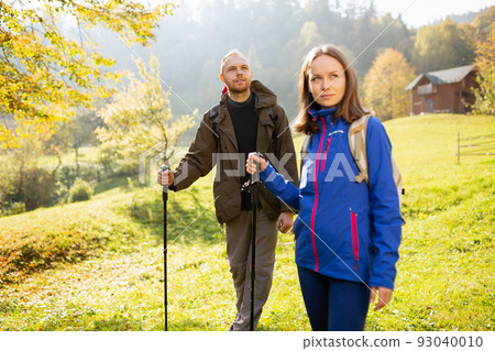 Portrait of a beautiful male traveler with a backpack and trekking stick traveling with his wife. 93040010