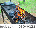 an empty brazier with a burning bonfire fire against the background of green grass preparing for a barbecue. 93040122