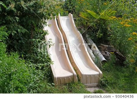 Pair of slides on a green slope Pair of slides on a green slope 93040436